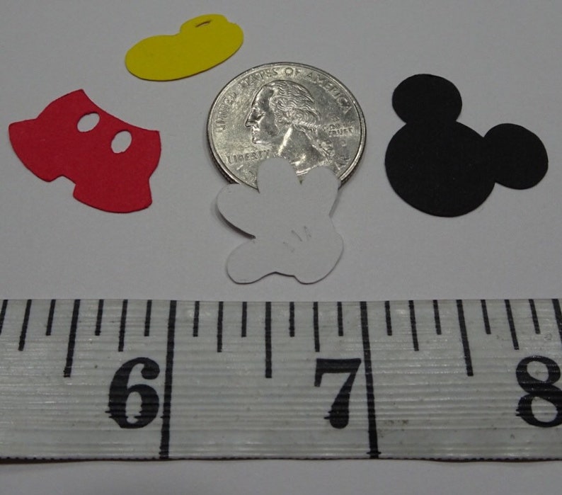 Puede incluir: Un conjunto de cinco recortes de papel con tem&aacute;tica de Mickey Mouse, que incluyen la cabeza de Mickey, pantalones cortos, un guante, un sombrero y una moneda de 25 c&eacute;ntimos para referencia de tama&ntilde;o.