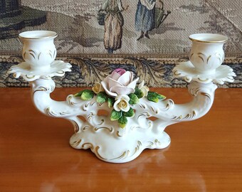 May include: White porcelain candle holder with two candle cups and a floral design featuring pink and white roses with green leaves.