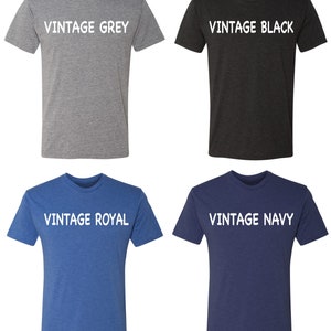 May include: Four t-shirts in different colors: vintage grey, vintage black, vintage royal, and vintage navy. Each shirt has the color name printed in white on the front.