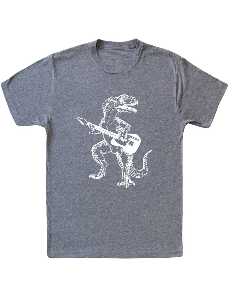 May include: A heather grey t-shirt with a white graphic of a dinosaur playing an electric guitar.