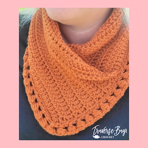Pode incluir: Cachecol de crochê laranja com um padrão de ponto texturizado. O cachecol tem formato triangular e borda ondulada. O texto "Traverse Bay Crochet" é visível no canto inferior direito.