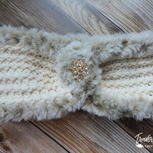May include: Cream-colored crocheted ear warmer with a faux fur trim and a decorative gold and rhinestone embellishment. The ear warmer is a cozy winter accessory.