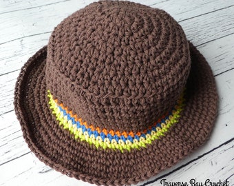 May include: A brown crochet hat with a wide brim. The hat has a colourful band with orange, yellow, blue, and green stripes. The hat is handmade and suitable for sun protection.