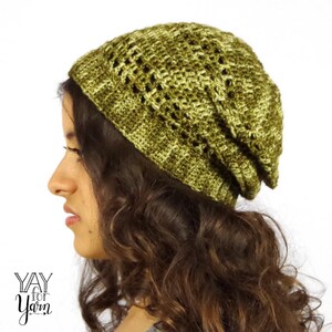 May include: A green and brown crocheted beanie with a slouchy fit. The beanie has a lacy pattern and is made with a soft yarn.