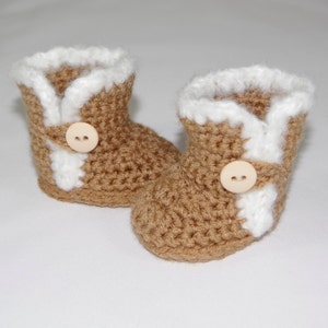 May include: A pair of brown crocheted baby booties with white trim and wooden buttons.