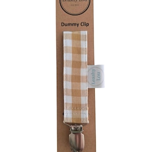 May include: A beige and white checkered fabric dummy clip with a silver clip. The clip is attached to a card with the text "Leashy Lou Est 2017" and "Dummy Clip" printed on it. The card also has the website "www.leashy-lou.com" printed on it.