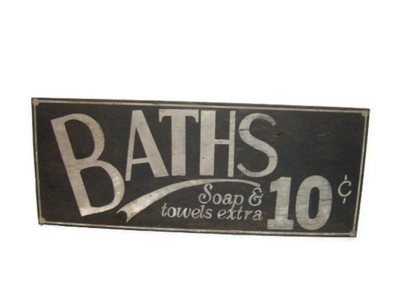 May include: A vintage wooden sign with white lettering advertising "BATHS 10&cent;" with the text "Soap & towels extra" underneath.