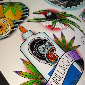 May include: A selection of tattoo designs in a traditional style. The designs include a gorilla head, a spider with cannabis leaves, lemons, and a Darth Vader-like character. The designs have bold outlines and vibrant colours.