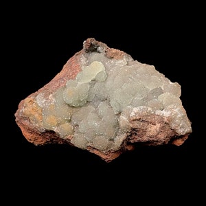 May include: A close-up of a light green and white mineral specimen with a rough, brown, rocky matrix. The mineral has a bubbly, rounded texture.