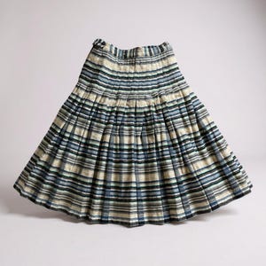 May include: A pleated skirt featuring a horizontal striped pattern in shades of navy blue, light blue, cream, and black. The garment has a fitted waistband with a button closure and a flared silhouette that extends to the hemline.