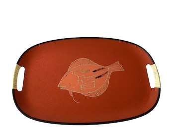 May include: A red oval serving tray with black trim and a white fish design. The fish has gold accents and is outlined in black.