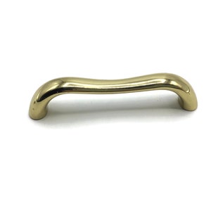 May include: A gold-toned, wavy, metal cabinet pull.