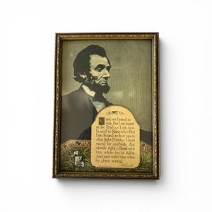 May include: Framed portrait of Abraham Lincoln in a dark suit, with a quote below. The frame is gold-toned with ornate detailing. The quote reads, "I am not bound to win, but I am bound to be true."