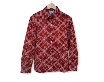 May include: A long-sleeved, button-down shirt in a deep red hue, adorned with a white geometric pattern. The shirt features a classic collar and cuffs, and is suspended from a wooden hanger against a white backdrop. The pattern consists of intersecting lines and dotted accents.