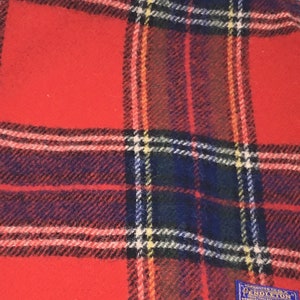 May include: Red plaid Pendleton wool blanket with a blue label that reads "Pendleton Woolen Mills, Portland, Oregon, USA, Pure Virgin Wool".