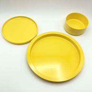 May include: Three yellow ceramic dishes, one small bowl and two plates, on a white background.