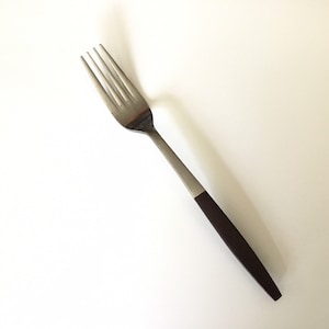 May include: A silver fork with a brown plastic handle. The fork is on a white background.