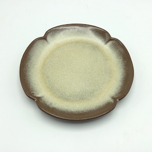 May include: A brown ceramic plate with a scalloped edge and a light beige interior. The plate has a speckled glaze.