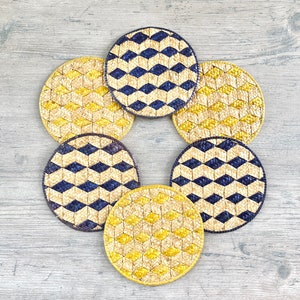 Peut inclure: Six dessous-de-verre ronds en osier avec un motif géométrique. Trois dessous-de-verre sont jaunes et noirs, et trois sont bleus et noirs.