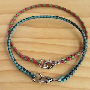 Puede incluir: Dos cordones de cuero trenzados con cierres met&aacute;licos. El cord&oacute;n de arriba es rosa y verde, el cord&oacute;n de abajo es negro y azul verdoso.
