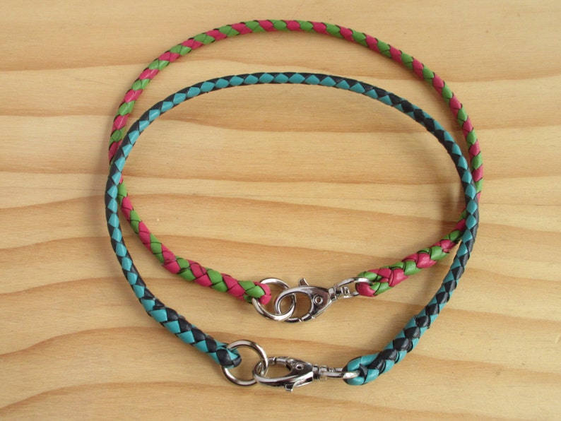 Puede incluir: Dos cordones de cuero trenzados con cierres met&aacute;licos. El cord&oacute;n de arriba es rosa y verde, el cord&oacute;n de abajo es negro y azul verdoso.