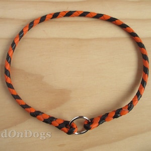 Pu&ograve; includere: Collare per cani in pelle intrecciata nero e arancio con un anello in metallo argentato.