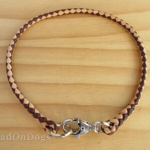 Puede incluir: Un collar de perro de cuero marr&oacute;n y beige con un cierre plateado. El collar est&aacute; trenzado con un patr&oacute;n de diamante.