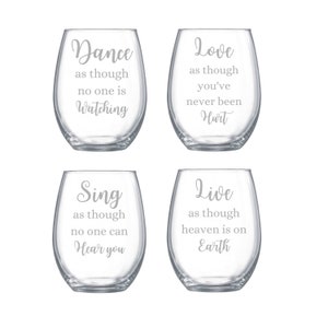 May include: A set of four clear stemless wine glasses, each featuring etched white text. The glasses display the phrases: Dance as though no one is Watching, Love as though you've never been Hurt, Sing as though no one can Hear you, and Live as though heaven is on Earth.