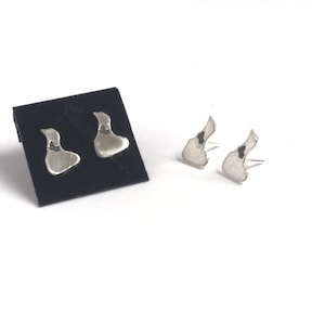 May include: A pair of silver earrings shaped like the state of Rhode Island.