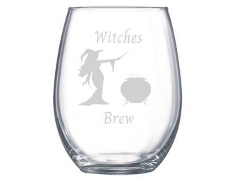 May include: A clear glass wine glass with an etched design of a witch stirring a cauldron with the text "Witches Brew".