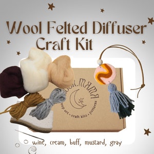 May include: Wool felted diffuser craft kit with a brown box, a white, cream, buff, mustard, and grey wool felt pieces, grey and mustard yarn, and a grey tassel. The box has the text "Moon Mama" and "oup art craft kits patterns".