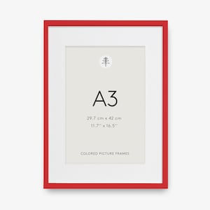 Puede incluir: Un marco de fotos rectangular rojo con un paspartú blanco. El centro contiene el texto A3, 29.7 cm x 42 cm, 11.7 inches x 16.5 inches y COLORED PICTURE FRAMES, con un pequeño dibujo lineal negro de un árbol sobre el texto.