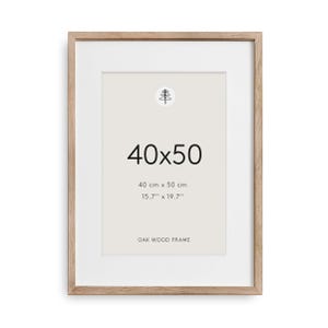 Può includere: Una cornice rettangolare in legno di rovere con un passe-partout bianco. Al centro è riportato il testo 40x50, 40 cm x 50 cm, 15.7'' x 19.7'' e OAK WOOD FRAME, insieme a una piccola icona circolare con un disegno a linee di un pino.