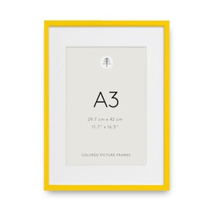 May include: A bright yellow rectangular picture frame with a white mat board. The center contains a light gray insert with a small tree icon, the text A3, the dimensions 29.7 cm x 42 cm and 11.7 inches x 16.5 inches, and the text COLORED PICTURE FRAMES.