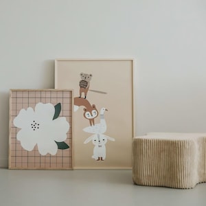 May include: Two framed wall art prints in light wood frames. One print features a large white flower on a grid background. The other print displays a vertical stack of illustrated animals including a squirrel, a fox, a goose, and a rabbit.