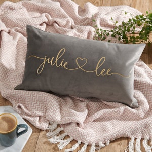 May include: A grey velvet cushion with the names "Julie & Lee" embroidered in gold script.