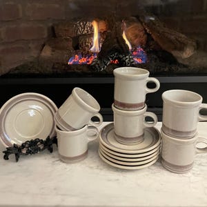 May include: Set of six vintage ceramic coffee cups and saucers with a white and brown striped design. The cups and saucers are arranged in a group on a white surface.