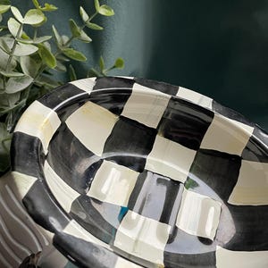 May include: Oval ceramic soap dish featuring a black and white chequered design. The dish has a raised rim and a glossy finish. A classic, bold design for any bathroom, with a nod to traditional style.
