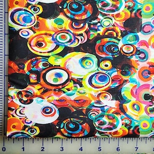 May include: A black fabric with a colorful, abstract pattern of overlapping circles. The circles are in shades of red, orange, yellow, green, blue, and purple.