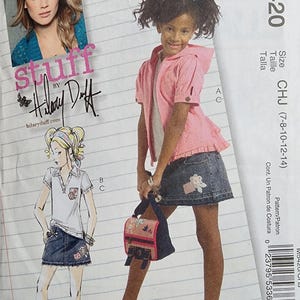 May include: McCall's sewing pattern featuring a young girl wearing a pink hooded jacket, denim skirt, and carrying a floral purse. The pattern includes illustrations and the text "stuff by Hilary Duff".