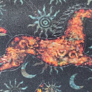 May include: A stylized orange horse silhouette on a black background with a repeating pattern of blue and white sun and moon shapes.