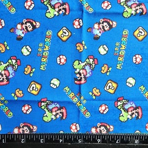 May include: Blue fabric featuring a repeating pattern of Super Mario World characters, including Mario, Yoshi, question mark blocks, and mushrooms. The words "Super Mario World" are also printed on the fabric.