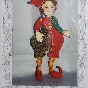 May include: A 16-inch standing doll pattern for making an elf with wired legs and fingers. The elf is wearing a red and green jester costume with a red hat and yellow and green trim.