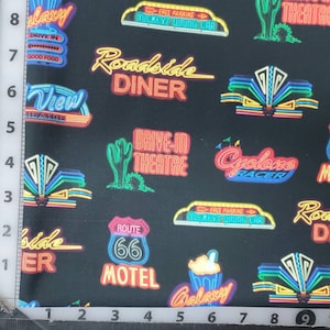 100% quilting cotton, PRICED by the 1/2 yard.  Jet black background with neon signs. Route 66, drive in theater dinner, mother road sign