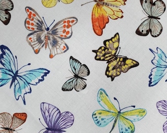 May include: A white fabric with a repeating pattern of colorful butterflies. The butterflies are in various shades of blue, yellow, orange, purple, and brown.