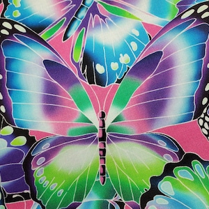 May include: A colorful fabric with a repeating pattern of butterflies. The butterflies are in shades of blue, purple, green, and pink. The background is a light pink.