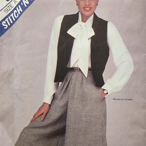 May include: A black and white houndstooth pattern culottes with a black vest and a white blouse with a large bow tie. The pattern is labeled "Stitch 'N Save" and "Size A (8-10-12)".