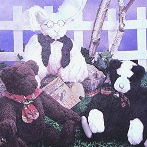 May include: Three plush stuffed animals, a white bunny wearing glasses and a black scarf, a brown bear wearing a red and white scarf, and a black and white dog wearing a red and black plaid scarf. The bunny is holding a book titled "Peter Rabbit".