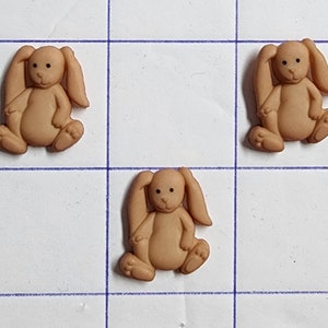 May include: Three brown plastic bunny buttons with black eyes and a white nose. The buttons are about 1 inch in diameter.