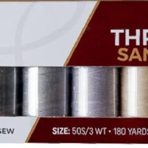 May include: A cotton thread set in a box, featuring eight spools in shades of gray, beige, and cream. The box has the text "COTTON THREAD SET SAND & STONE" and "Madam Sew". Each spool contains 180 yards of thread.